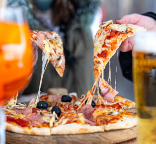 Pizza savoyarde au jambon, champignons et olives servie en terrasse enneigée