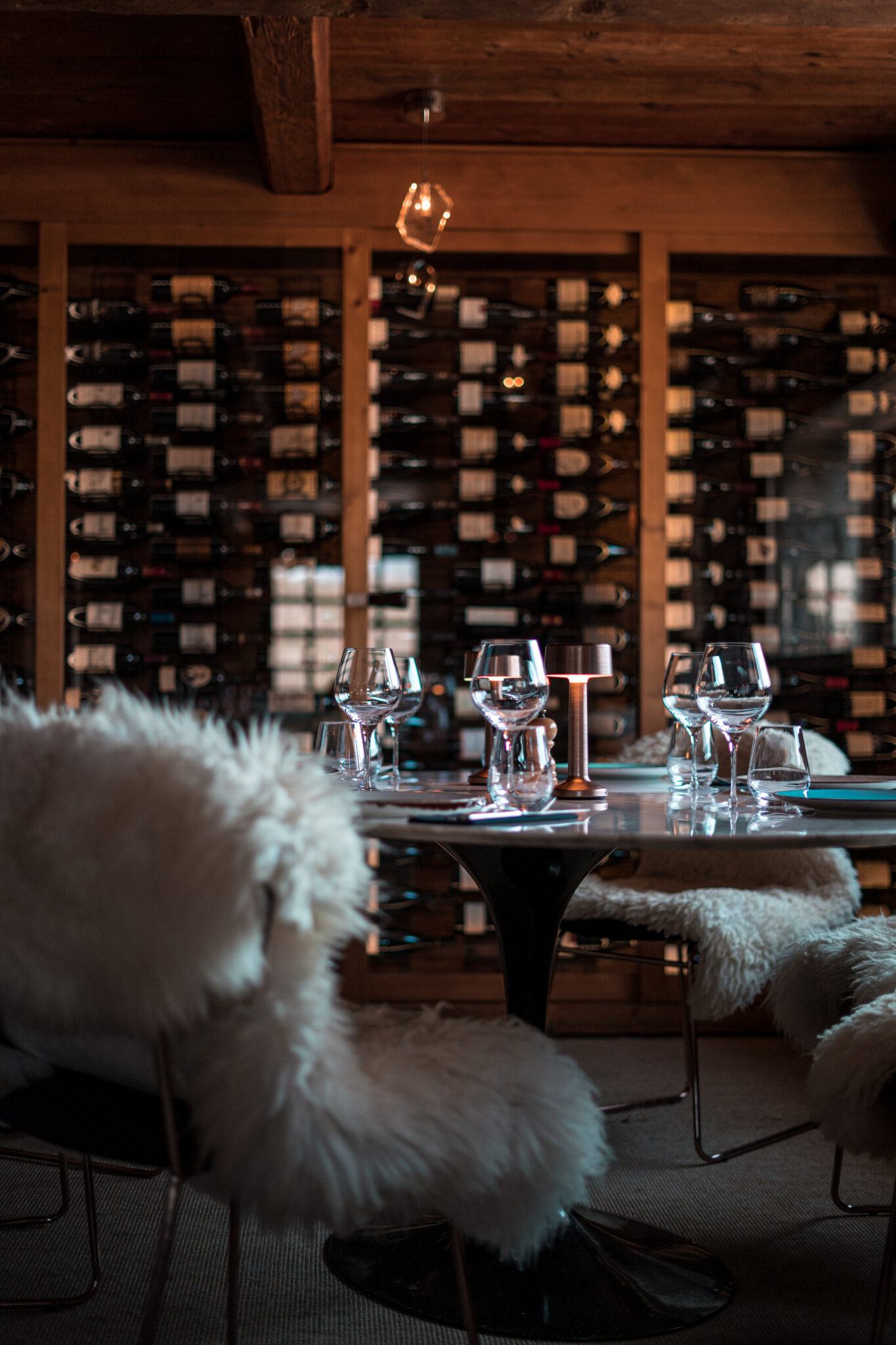 Gros plan sur les étagères à vins dans l’intérieur en bois du restaurant des Chalets des Praz à La Clusaz