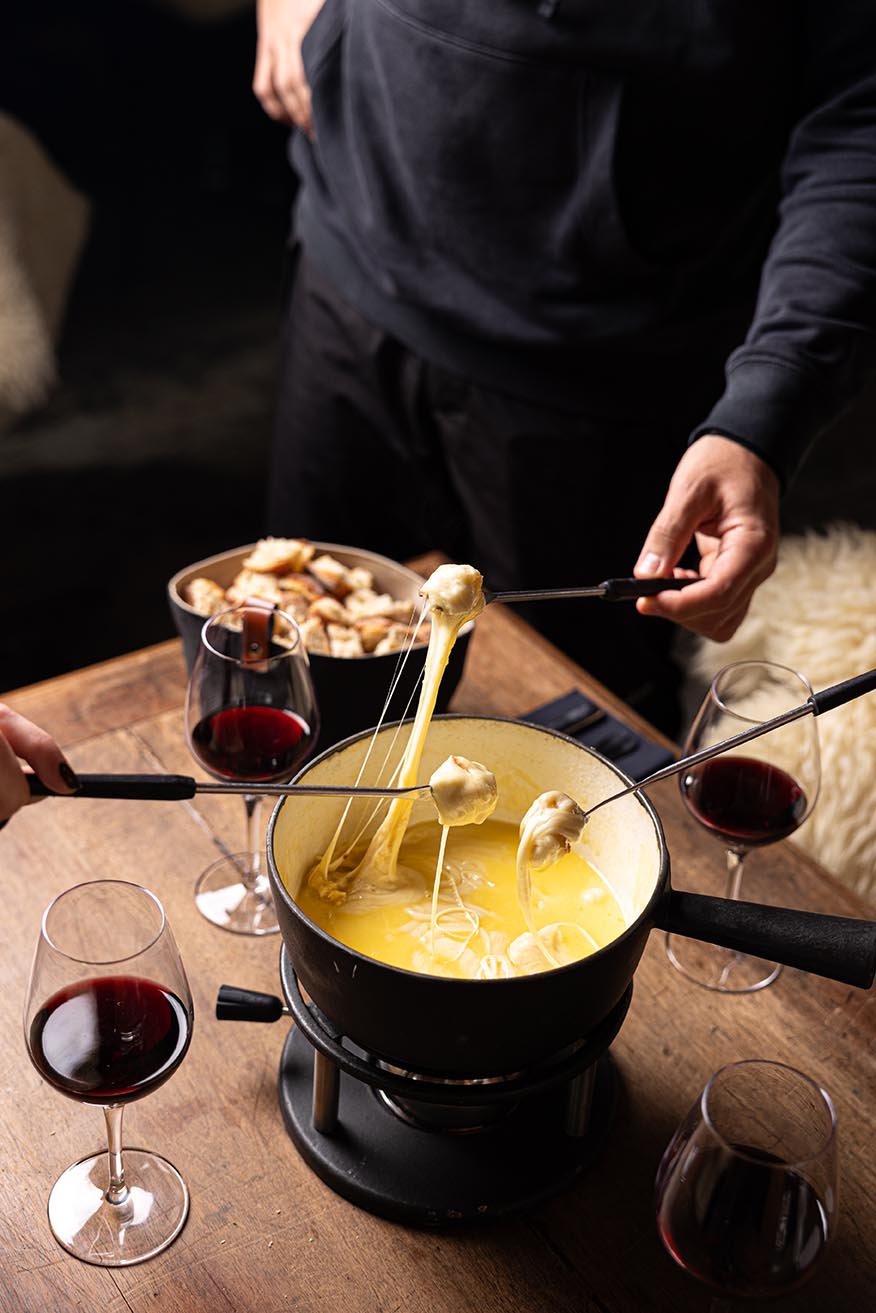 Fondu savoyarde au fromage avec pain et charcuterie sur une table en bois