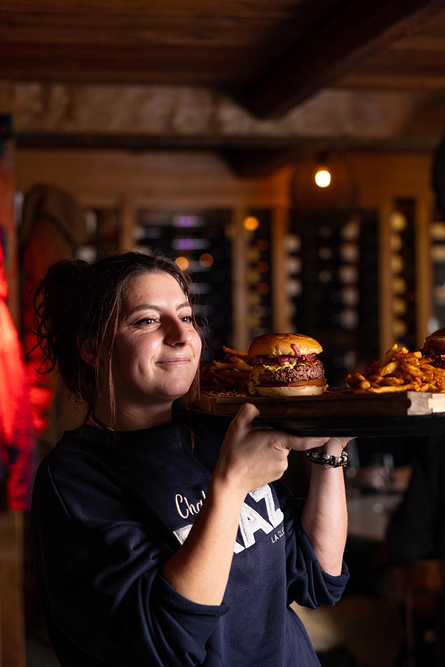 Serveuse souriante servant un burger gourmand dans un restaurant