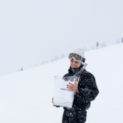 Skieuse tenant un seau Minuty rempli de neige et bouteille de rosé – Chalet des Praz
